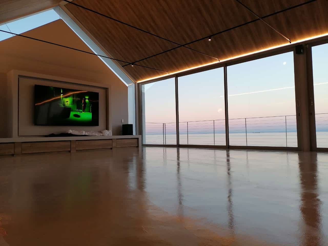 Polished seamless microcement lounge floor reflecting a sunset ocean view through floor-to-ceiling glass