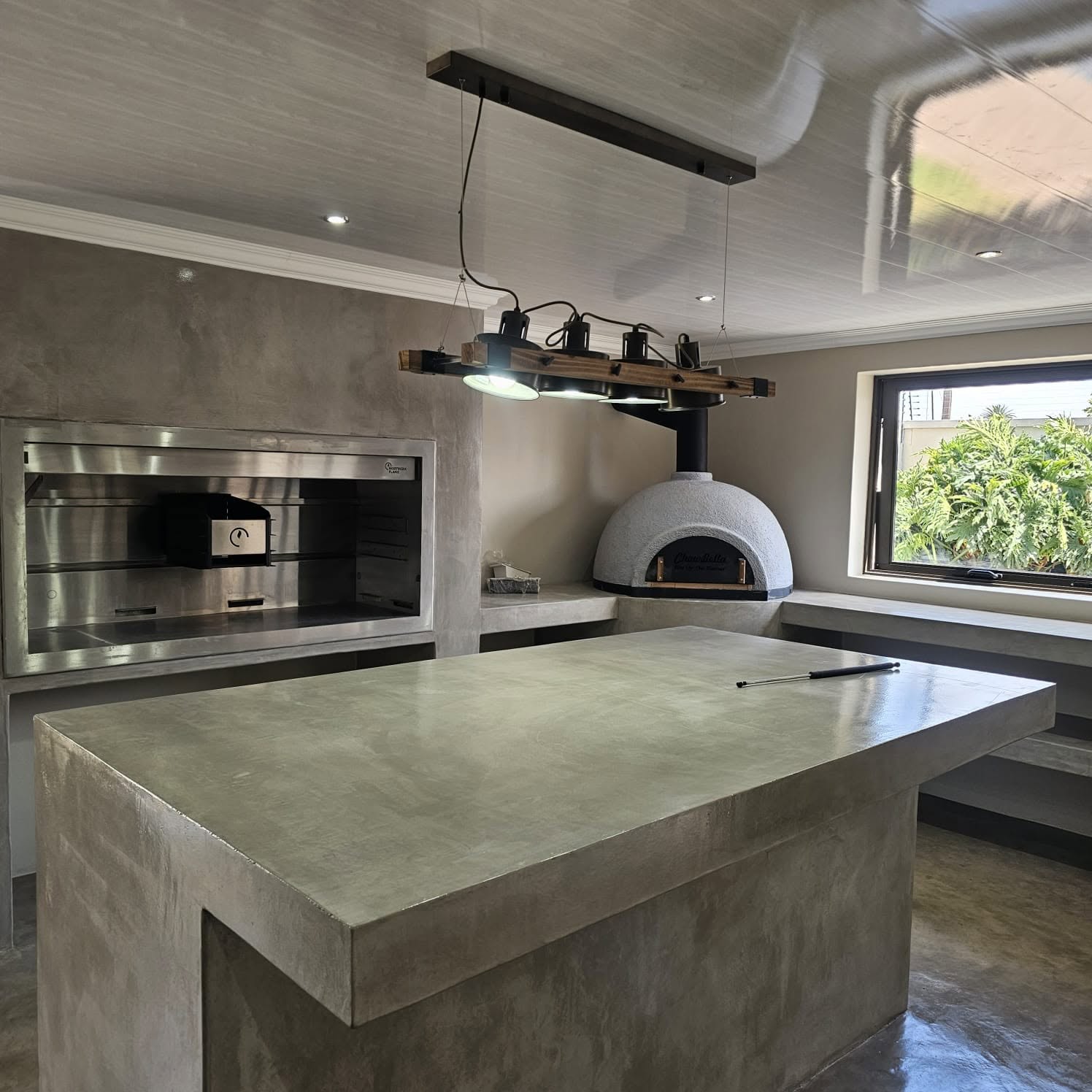 Grey microcement outdoor kitchen counter and pizza oven surround with a seamless trowelled finish