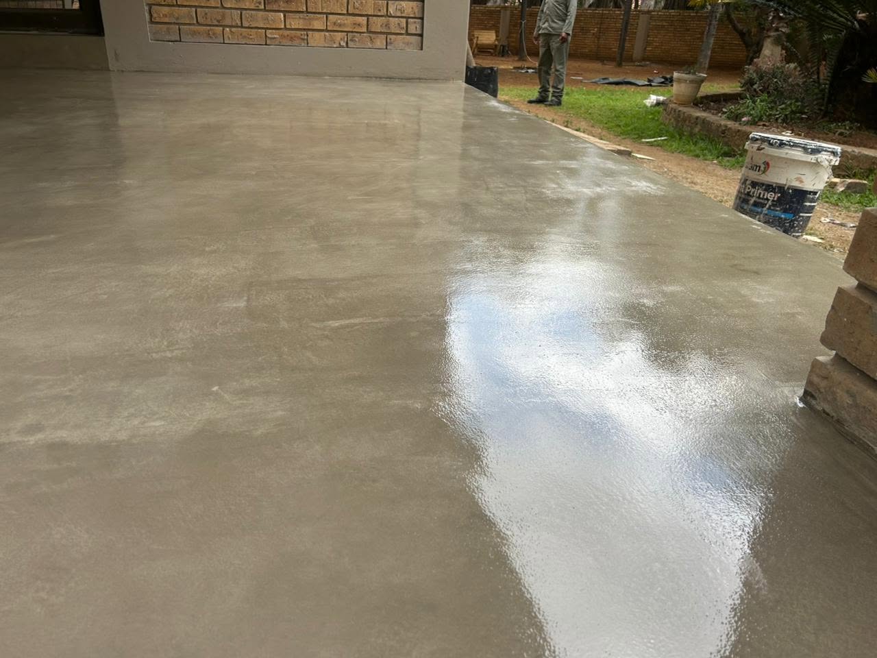 Resurfaced concrete patio floor, half sealed and glossy, half still matte, showing the finish part-applied